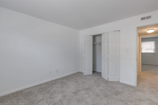a living room with white walls and a door to a closet