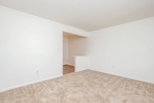 an empty living room with white walls and carpet