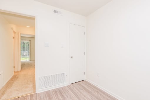 a bedroom with white walls and a door to a hallway