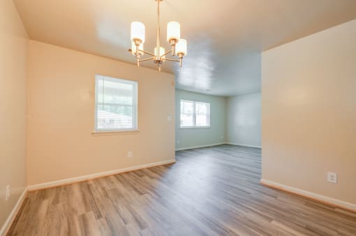 an empty living room with hard wood floors and a chandelier