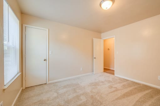 a spacious living room with carpet and a door to a hallway