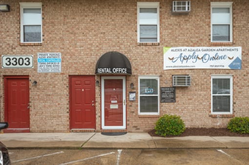 the front of a brick building with two red doors and a sign that reads the