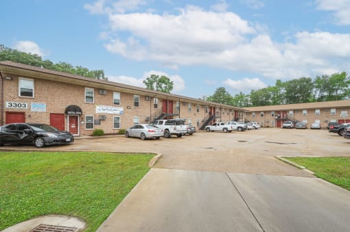 a parking lot in front of a brick building with cars parked