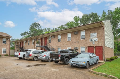 a brick apartment building with cars parked in front