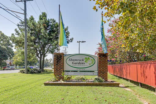 the sign for shamrock gardens in front of a brick fence