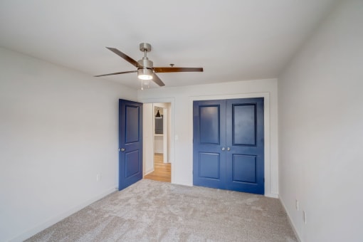 a empty room with blue doors and a ceiling fan