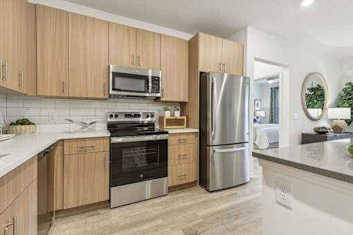 a modern kitchen with stainless steel appliances and wooden cabinets at Tapestry Headwaters in Kissimmee, FL