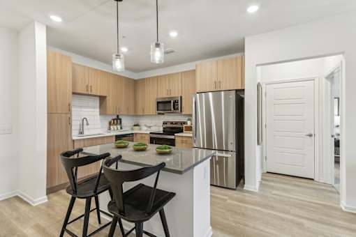 island kitchen with stainless steel appliances and designer lighting at Tapestry Headwaters Apartments in Kissimmee, FL
