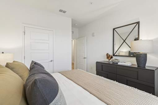 a bedroom with a large bed and a dresser with a mirror
