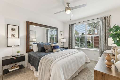 Primary bedroom with large window and ceiling fan at Tapestry Headwaters Apartments in Kissimmee, FL