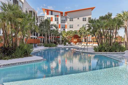 Swimming Pool with Seating and Umbrellas at Tapestry Headwaters in Kissimmee, FL