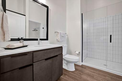 A bathroom with standing shower and tile surround and a white countertop