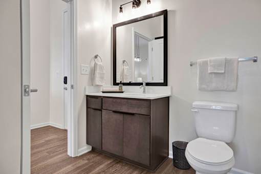 A bathroom with a white countertop, high ceilings, tile shower surround and luxury LVP floors