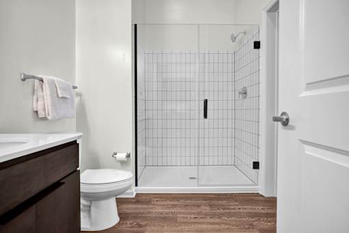 A modern bathroom with white countertops and walk-in shower with tile surround