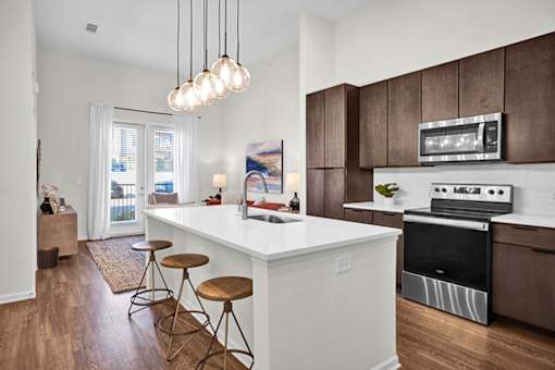 A modern kitchen with a white island, white countertop and brown cabinetry