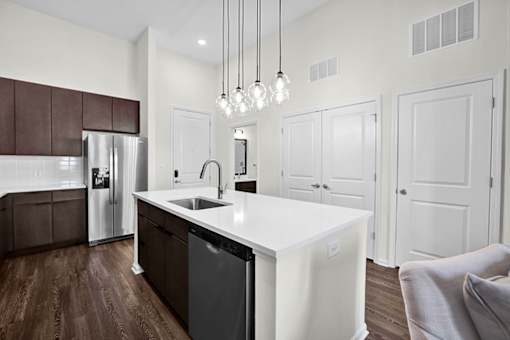 A modern kitchen with a white island and dark brown cabinets, high ceilings and beautiful lighting.