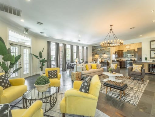 a living room with yellow couches and chairs and a kitchen