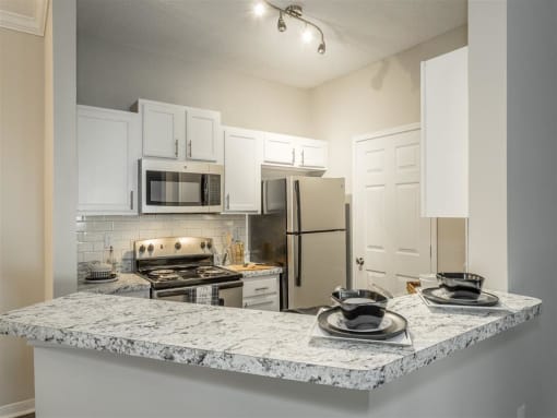 a kitchen with a granite counter top and a stainless steel refrigerator