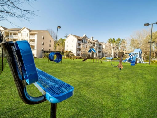 a playground with a blue bench in front of an apartment building