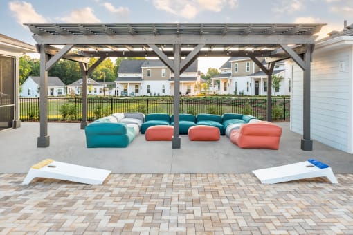 a patio with couches and a pergola with houses in the background