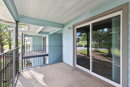 A balcony with a black railing and a sliding glass door.