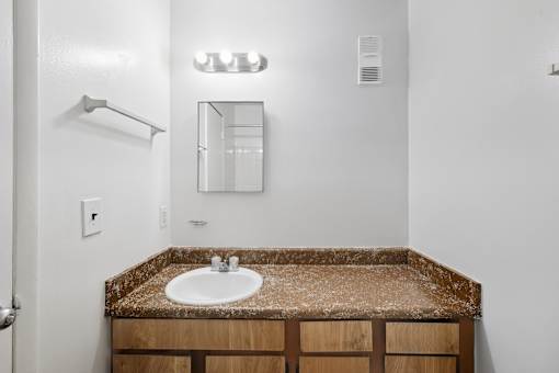 A bathroom with a brown granite counter top and a white sink.