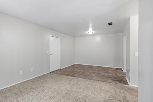 A room with a carpeted floor and a ceiling fan.