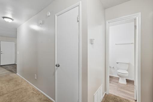 A white bathroom with a toilet and a white door.