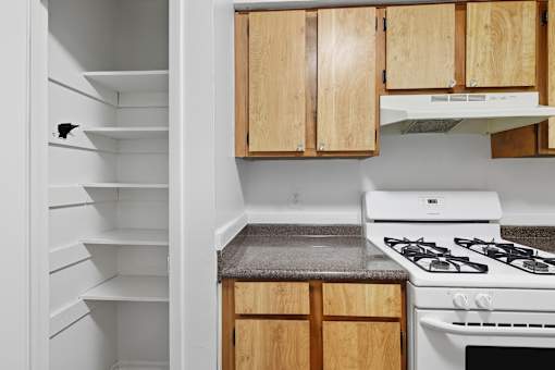 A kitchen with a white stove and wooden cabinets.
