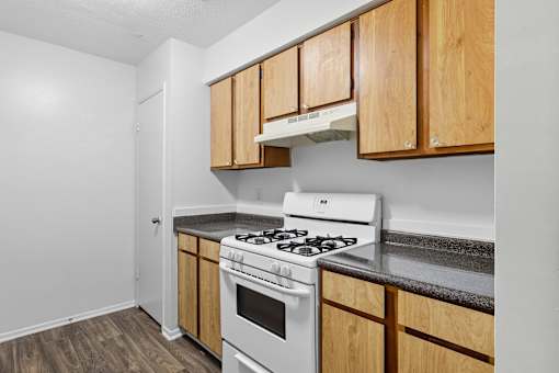 A kitchen with a white stove and wooden cabinets.