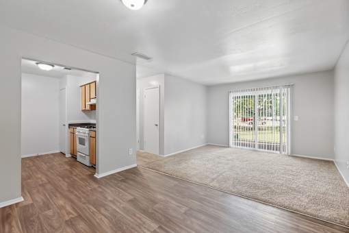 A spacious living room with a kitchenette and sliding glass doors.