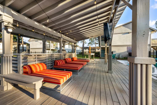 poolside covered patio with lounge chairs and TV at Retreat at Brightside Apartments in Baton Rouge, LA