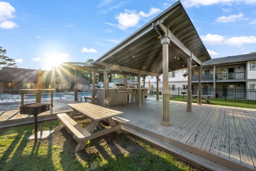 a deck with a picnic table and grill near swimming pool at Retreat at Brightside Apartments in Baton Rouge, LA