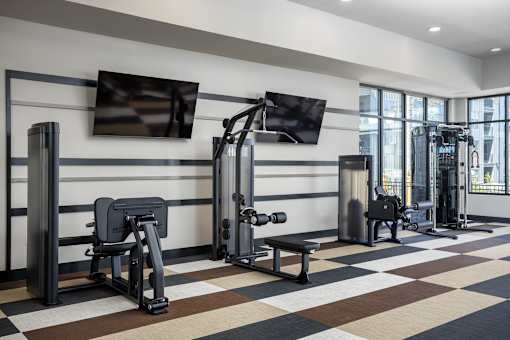 A gym with a variety of equipment including a bench, weights, and a television.