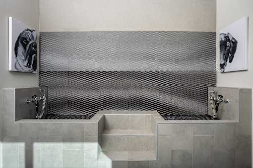 A bathroom with a grey tiled shower area and a grey sink.