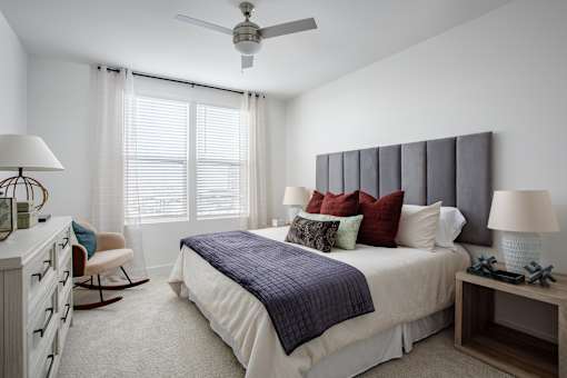 A bedroom with a bed, chair, and ceiling fan.