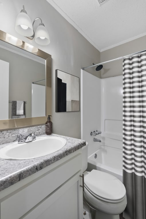 a bathroom with a sink toilet and bathtub  Living Room with wood flooring at Midtown Oaks Townhomes in Mobile, AL