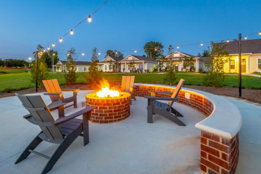a fire pit with chairs and a bench on a concrete patio with houses in the background