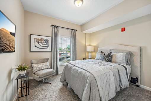 A bedroom with a large bed and a chair.