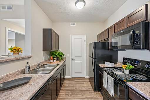A kitchen with black appliances and brown cabinets.