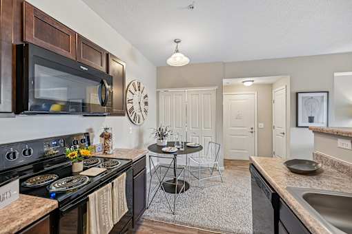 A kitchen with a black stove top oven and a black microwave above it.
