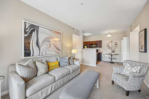 A living room with a grey couch and a large abstract painting on the wall.