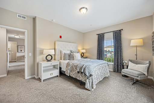 A bedroom with a large bed and a chair.