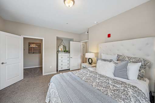 A bedroom with a large bed and a nightstand with a lamp.