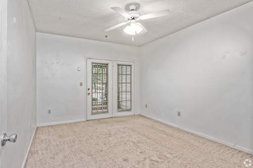 A room with a ceiling fan and a door with a window.