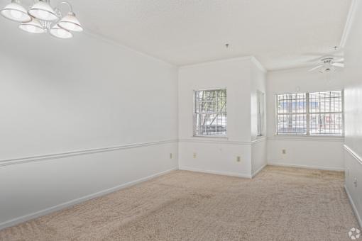A spacious room with a carpeted floor and a ceiling fan.
