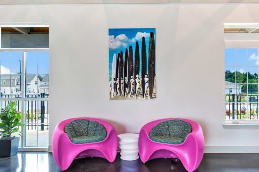 a room with two pink chairs and two surfboards on the wall