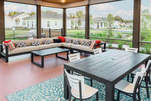 a screened patio with a couch table and chairs and large windows cottage at Anthem Apartments and Cottages in Huntsville, Alabama