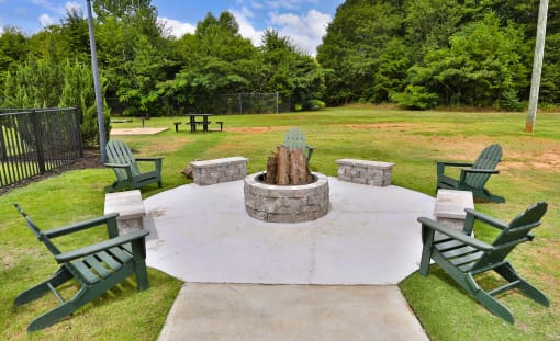a fire pit in the middle of a yard with chairs around it