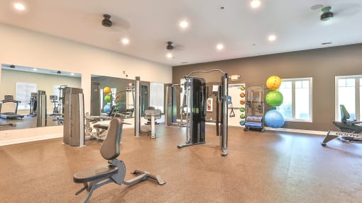 a gym with cardio equipment and weights in a building with windows